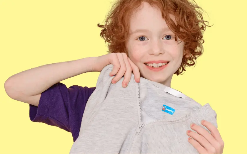 Bambino che mostra un maglione con un'etichetta termoadesiva