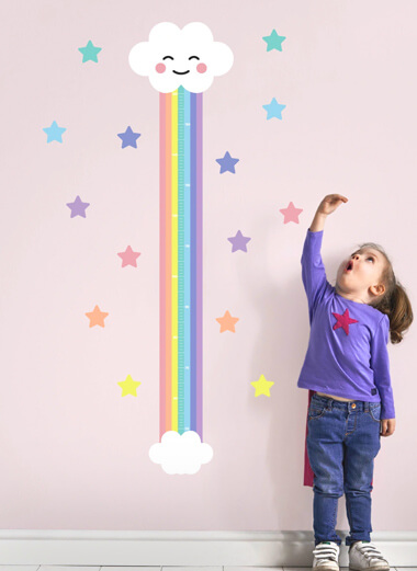My Nametags grafico dell'altezza della nuvola arcobaleno su un muro rosa con una bambina in piedi accanto ad esso